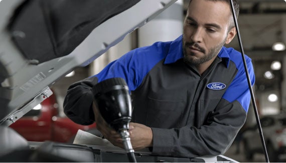 Ford technician performing vehicle service under open hood